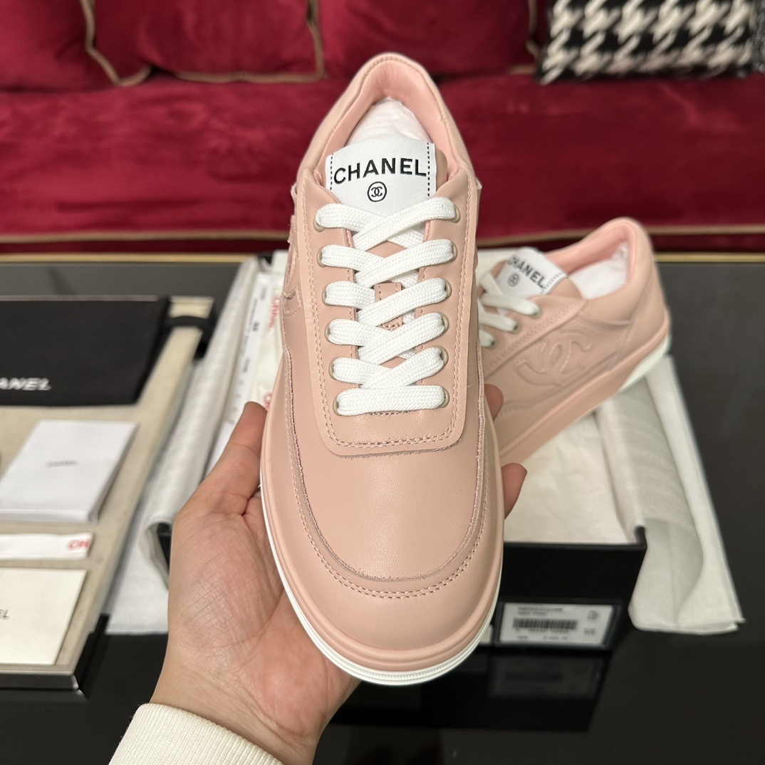 A pair of pink Chanel leather low-top sneakers with white laces and embossed CC logo sitting in their original box with accessories. - Hình 3