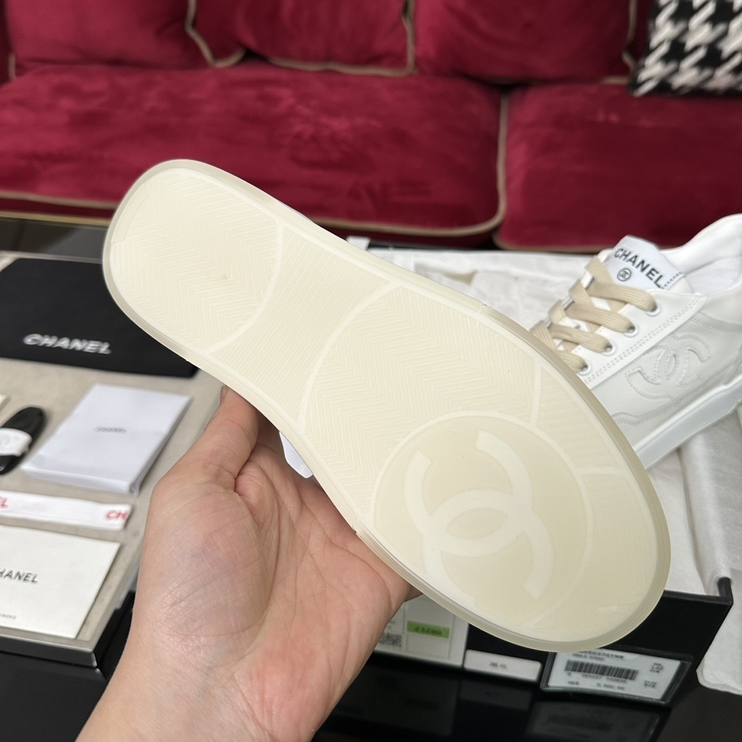 Authentic white Chanel leather sneakers with embossed CC logo and cream laces in original luxury packaging. - Hình 9