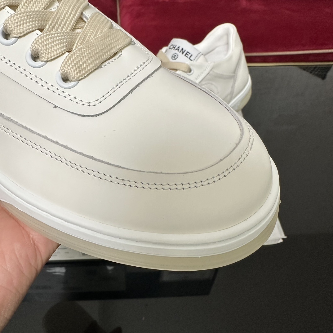 Authentic white Chanel leather sneakers with embossed CC logo and cream laces in original luxury packaging. - Hình 6