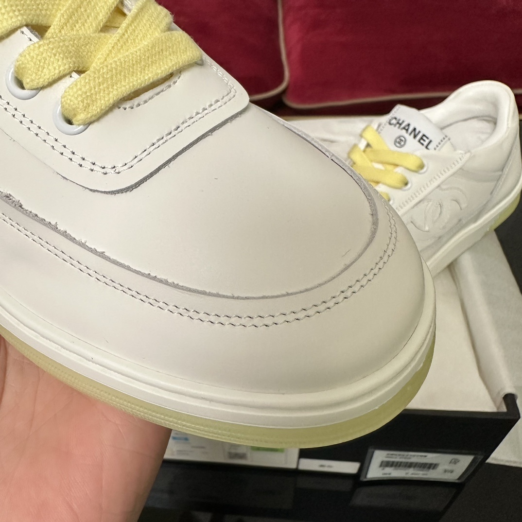Pair of Chanel white leather sneakers with yellow laces and translucent yellow sole in a black designer box - Hình 6