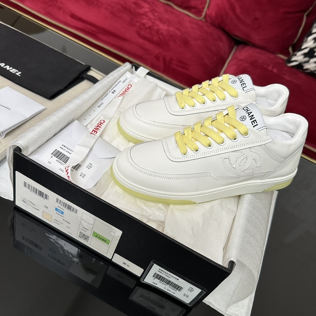 Pair of Chanel white leather sneakers with yellow laces and translucent yellow sole in a black designer box - Hình 2