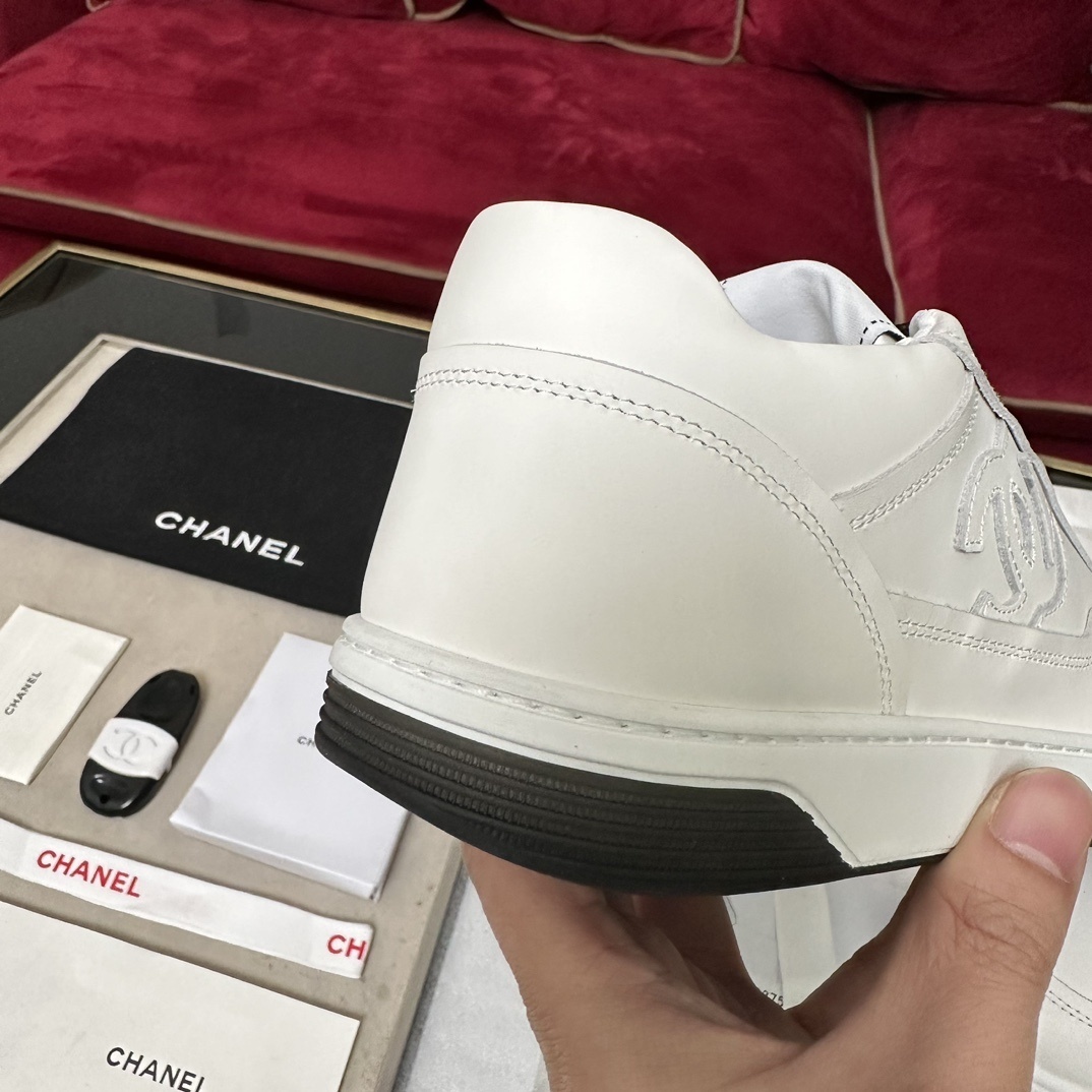 Premium white Chanel low-top leather sneakers with black laces and embossed CC logo, displayed with original luxury packaging. - Hình 8