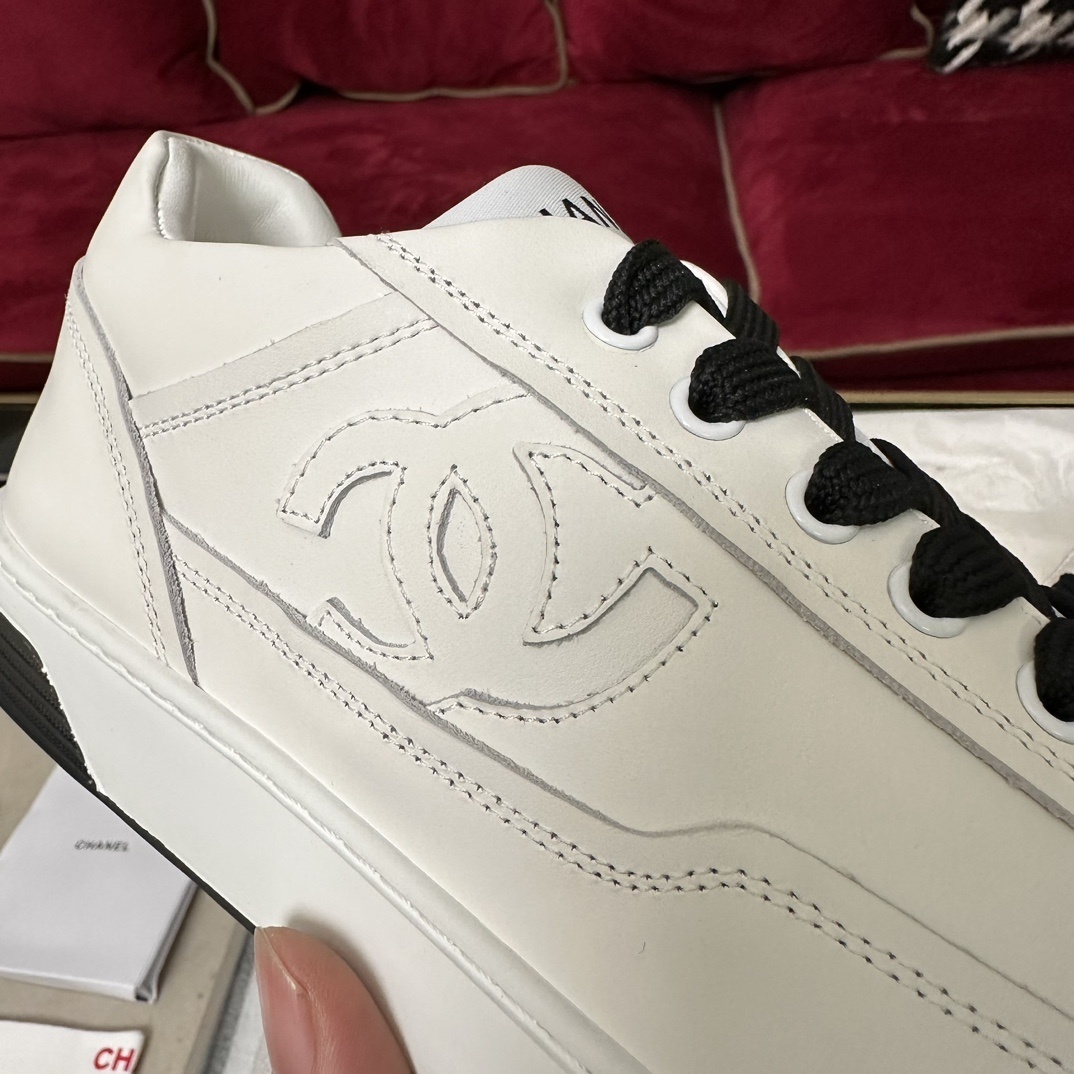 Premium white Chanel low-top leather sneakers with black laces and embossed CC logo, displayed with original luxury packaging. - Hình 7