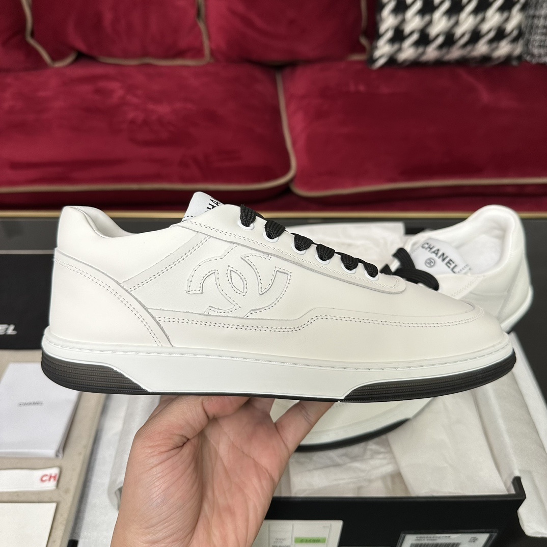 Premium white Chanel low-top leather sneakers with black laces and embossed CC logo, displayed with original luxury packaging. - Hình 5