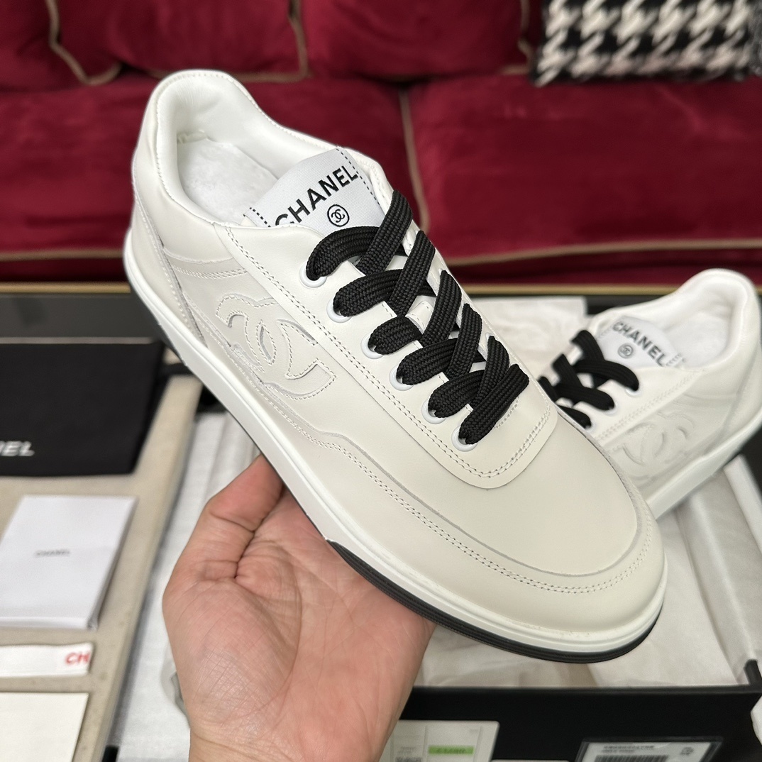 Premium white Chanel low-top leather sneakers with black laces and embossed CC logo, displayed with original luxury packaging. - Hình 4