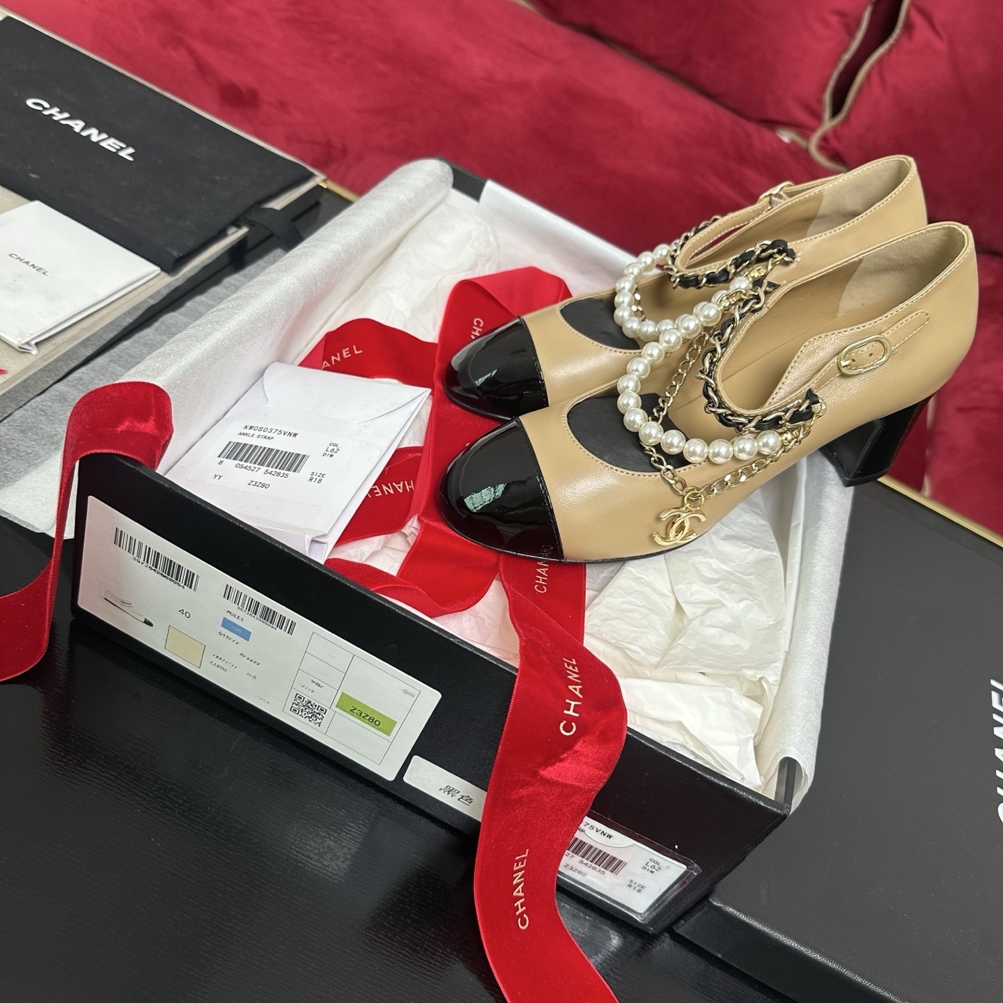 Chanel beige and black two-tone Mary Jane pumps with pearl and gold chain accents and CC logo charm in original packaging. - Hình 2