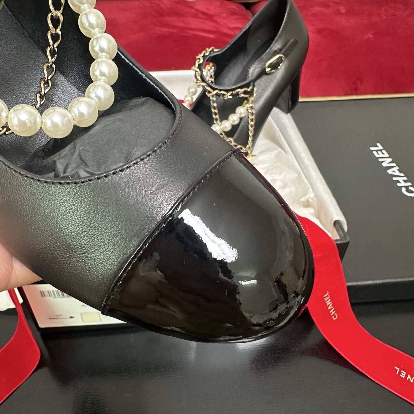 Luxury black Chanel Mary Jane pumps with patent leather cap toes and decorative pearl and gold chain straps displayed in a branded box. - Hình 6