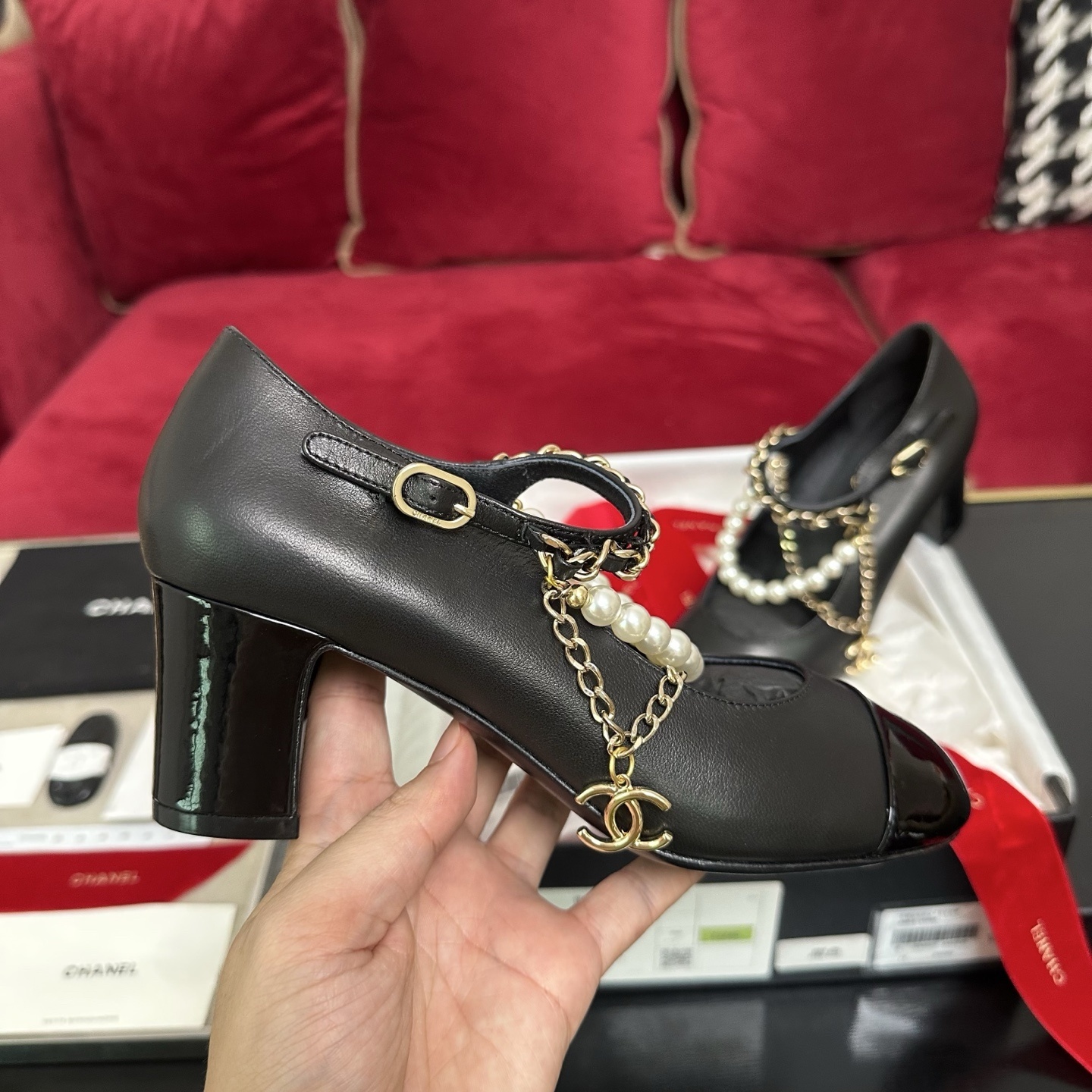 Luxury black Chanel Mary Jane pumps with patent leather cap toes and decorative pearl and gold chain straps displayed in a branded box. - Hình 5