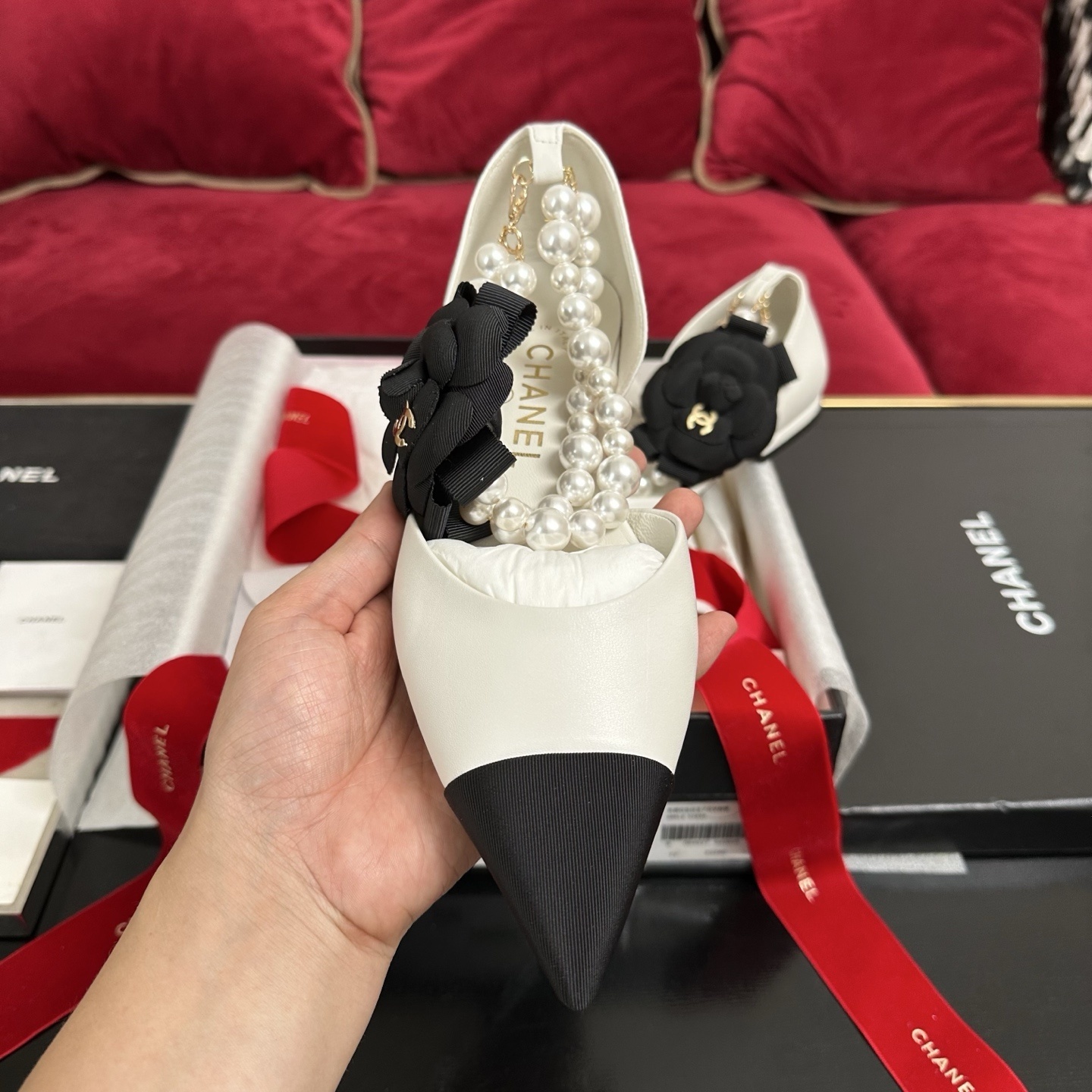 Chanel white leather mules with black cap toe, pearl ankle strap, and black camellia flower charm in original packaging. - Hình 3