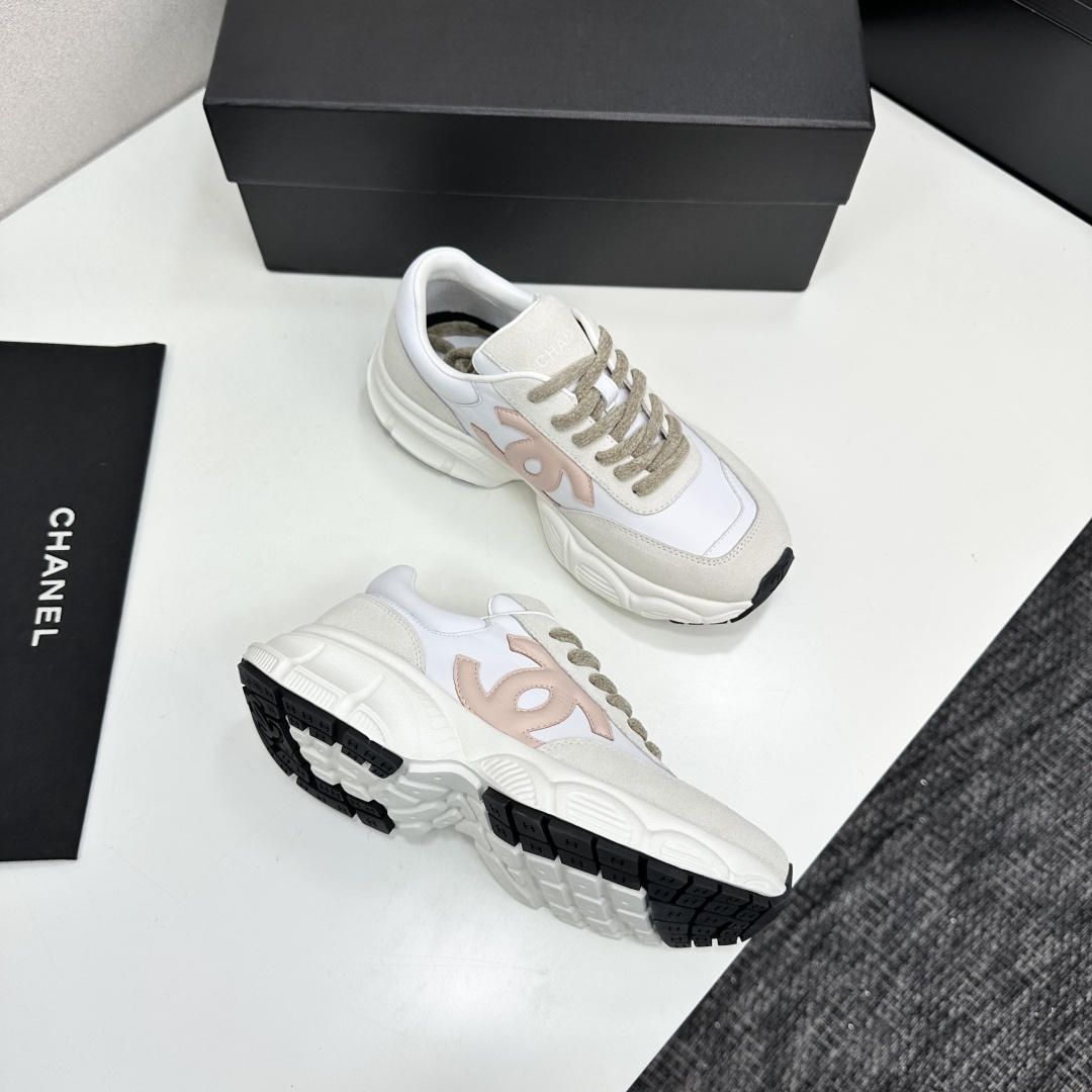 A pair of Chanel chunky sneakers in white leather and cream suede featuring a pink CC logo on the side, displayed on a black box. - Hình 10