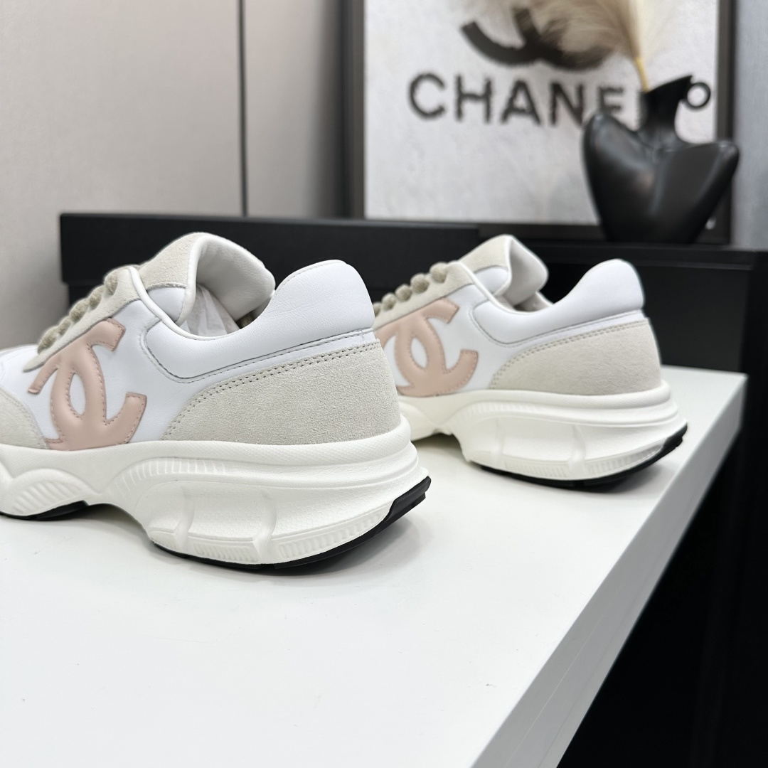 A pair of Chanel chunky sneakers in white leather and cream suede featuring a pink CC logo on the side, displayed on a black box. - Hình 9