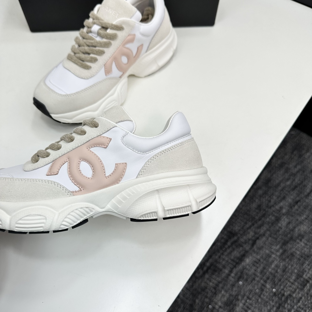 A pair of Chanel chunky sneakers in white leather and cream suede featuring a pink CC logo on the side, displayed on a black box. - Hình 8