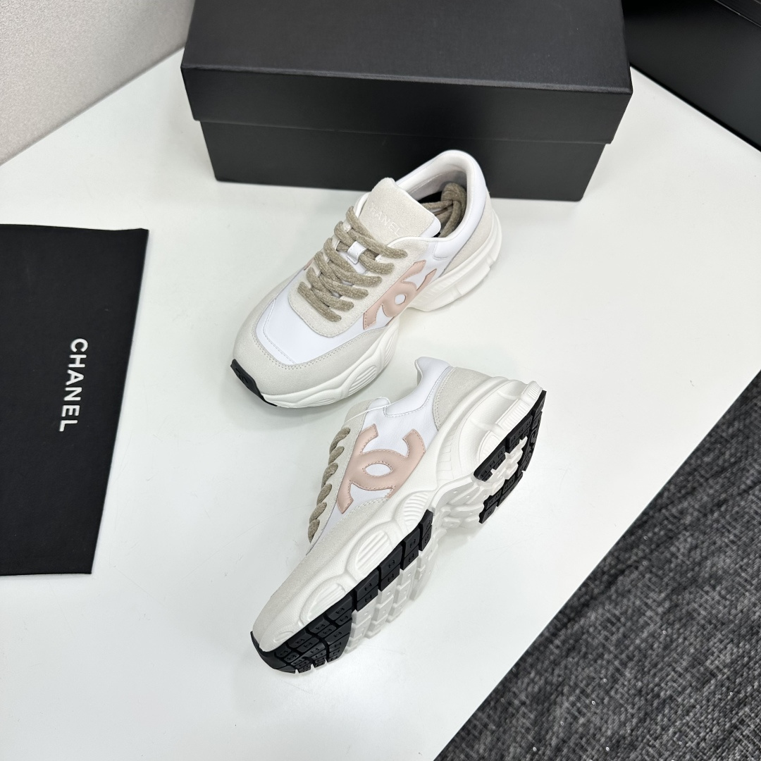 A pair of Chanel chunky sneakers in white leather and cream suede featuring a pink CC logo on the side, displayed on a black box. - Hình 7