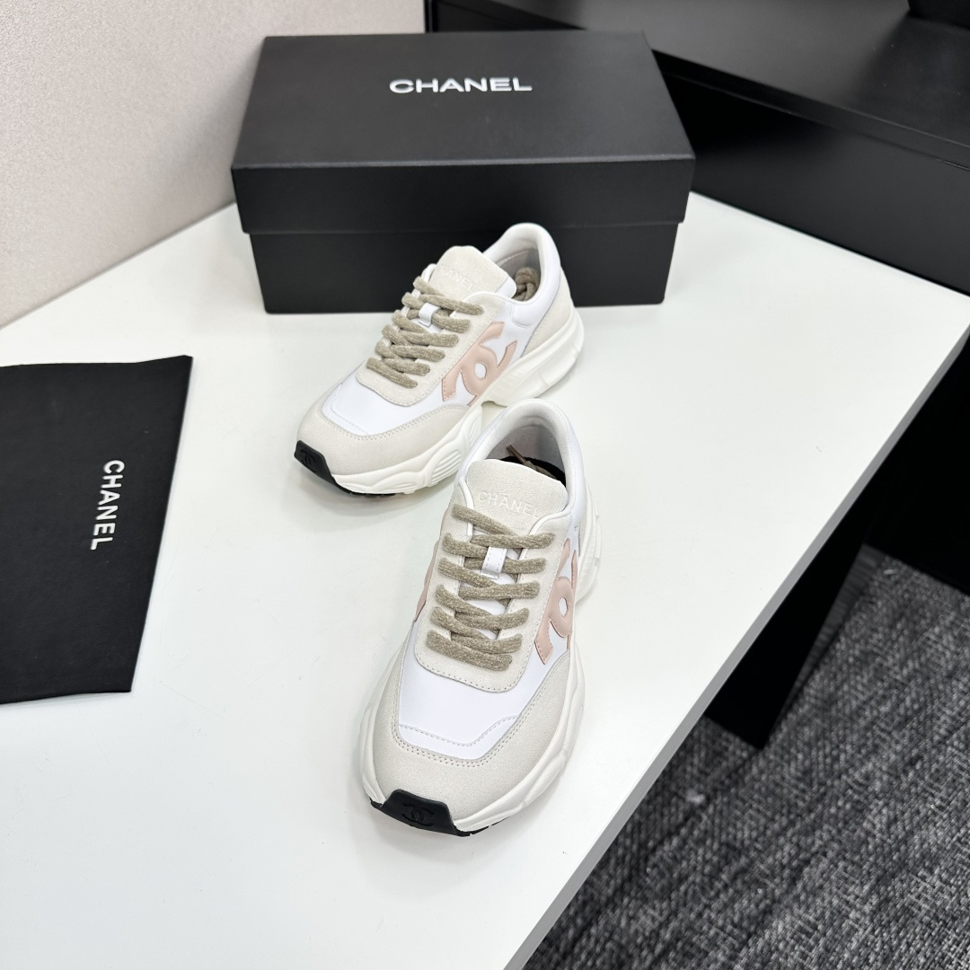 A pair of Chanel chunky sneakers in white leather and cream suede featuring a pink CC logo on the side, displayed on a black box. - Hình 6