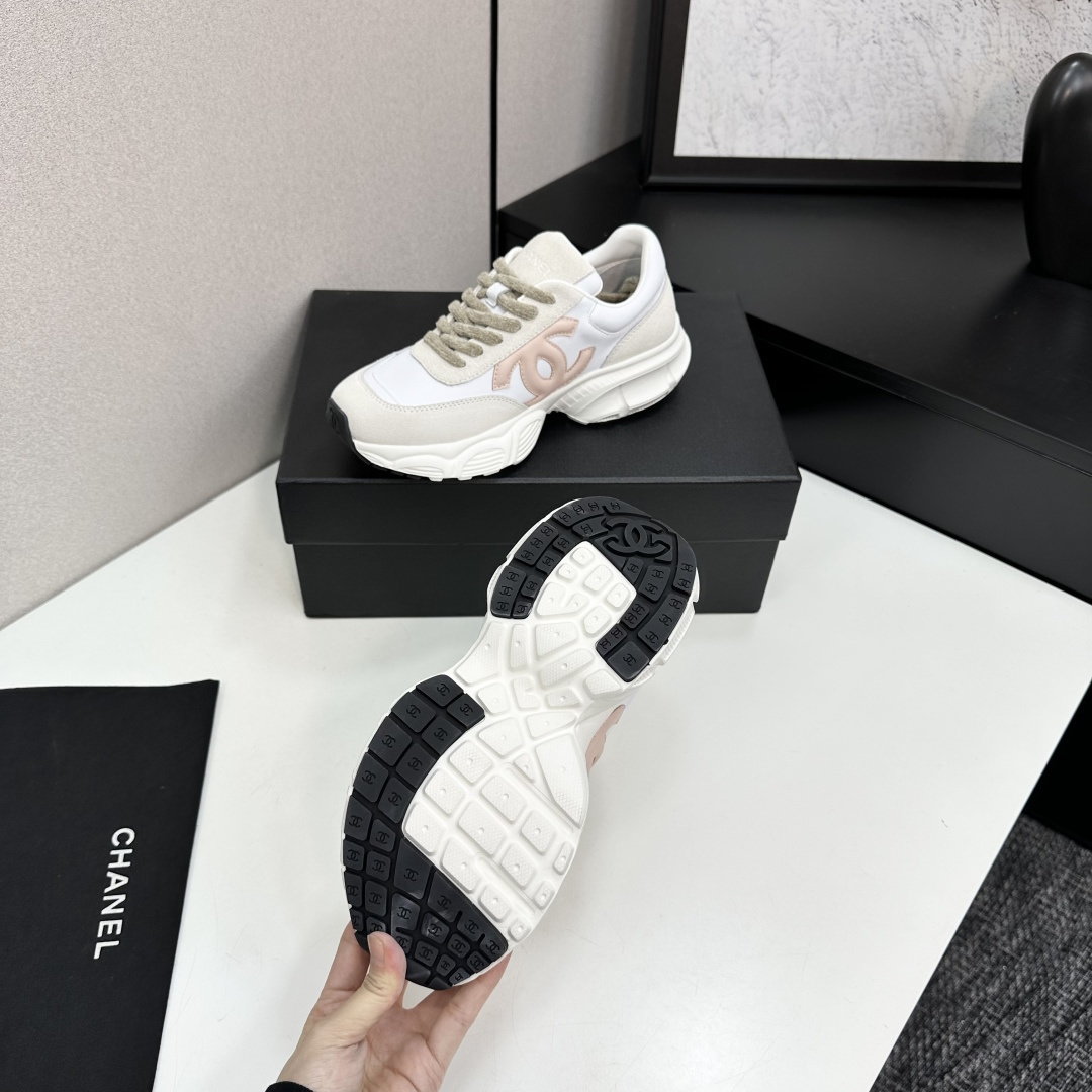 A pair of Chanel chunky sneakers in white leather and cream suede featuring a pink CC logo on the side, displayed on a black box. - Hình 5