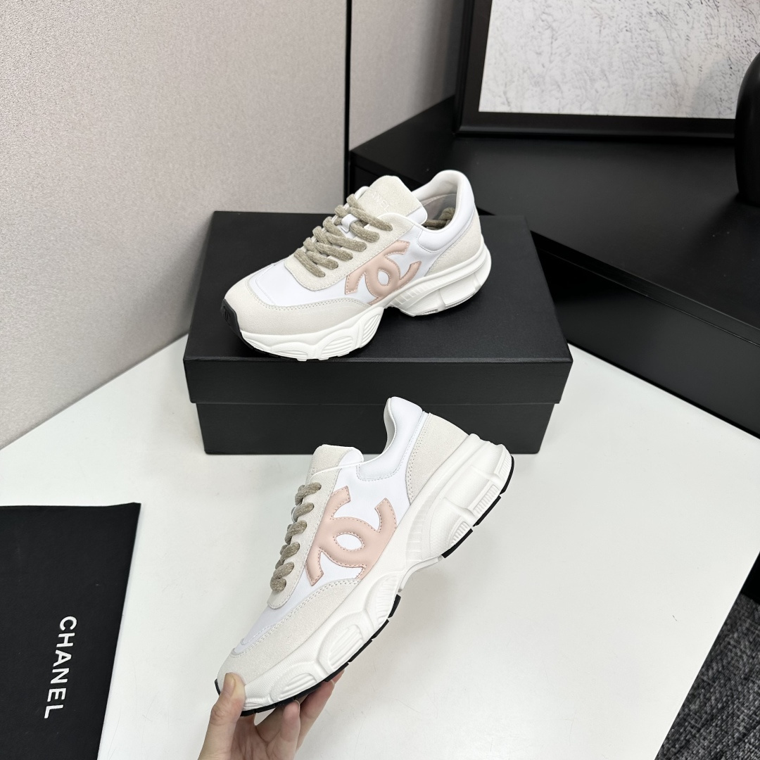 A pair of Chanel chunky sneakers in white leather and cream suede featuring a pink CC logo on the side, displayed on a black box. - Hình 4
