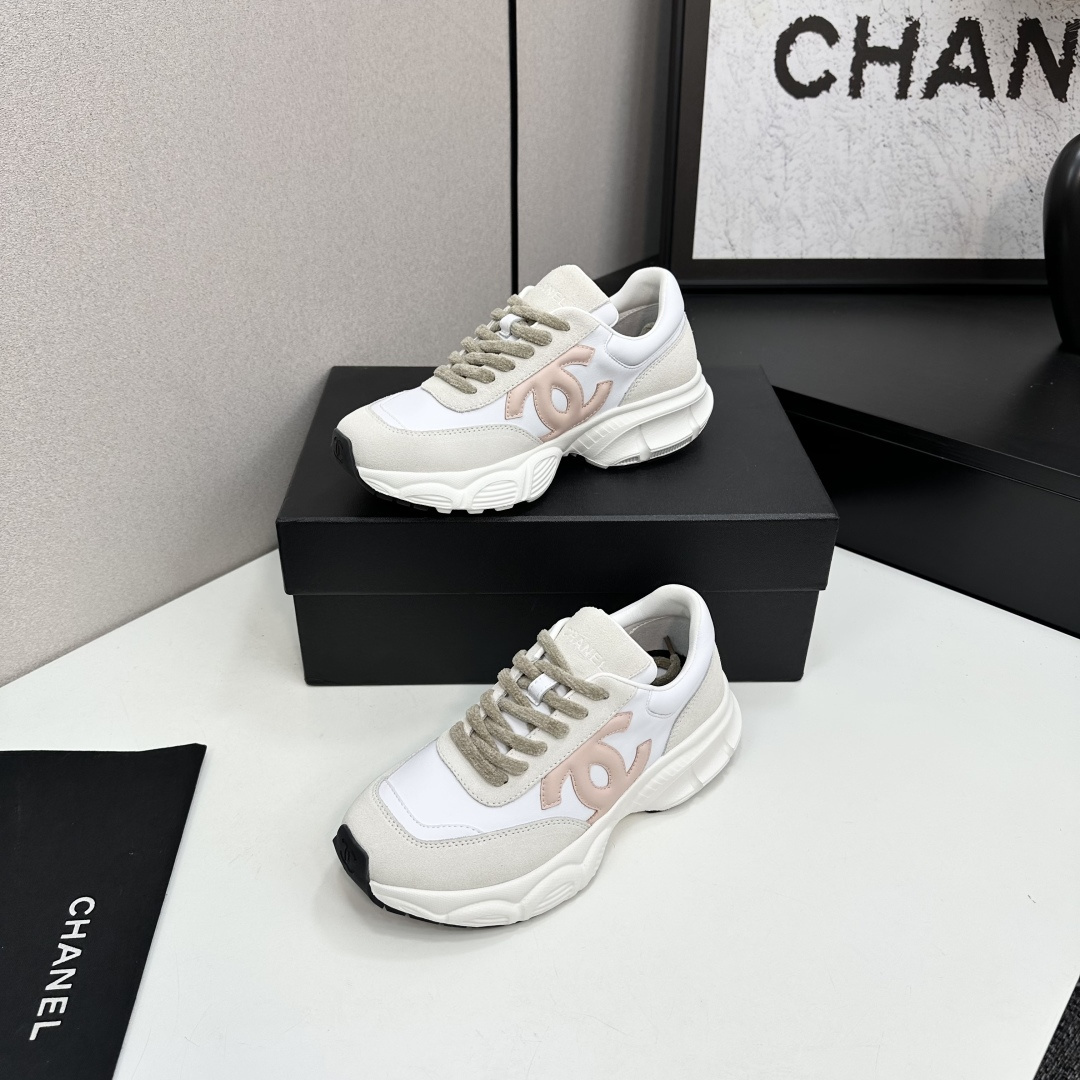 A pair of Chanel chunky sneakers in white leather and cream suede featuring a pink CC logo on the side, displayed on a black box. - Hình 3