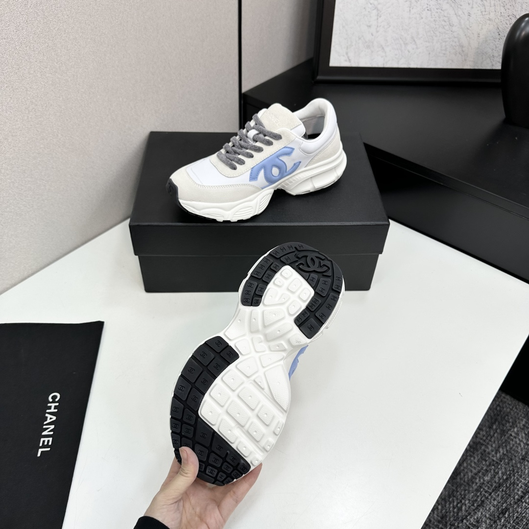 Chanel white and beige sneakers with a light blue CC logo and grey laces displayed on a black brand box - Hình 5