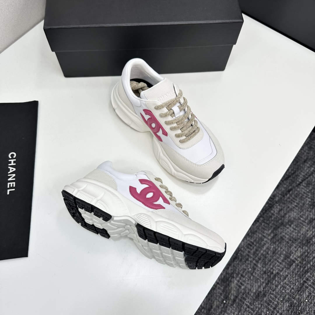 Side view of white and cream Chanel sneakers with a pink CC logo and chunky white soles on a black box. - Hình 10