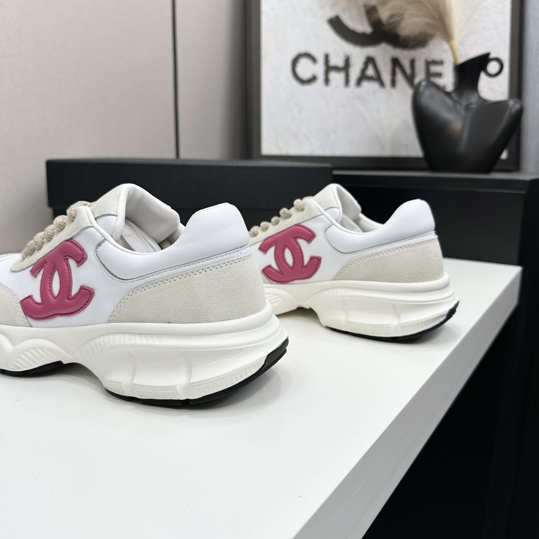 Side view of white and cream Chanel sneakers with a pink CC logo and chunky white soles on a black box. - Hình 9