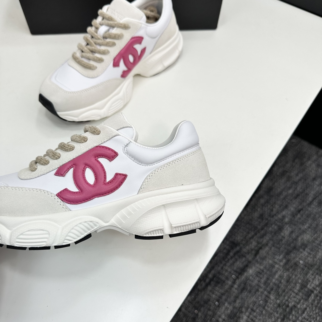 Side view of white and cream Chanel sneakers with a pink CC logo and chunky white soles on a black box. - Hình 8
