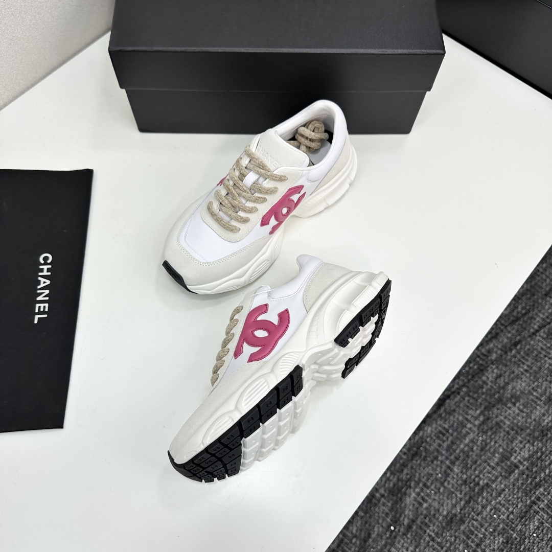 Side view of white and cream Chanel sneakers with a pink CC logo and chunky white soles on a black box. - Hình 7