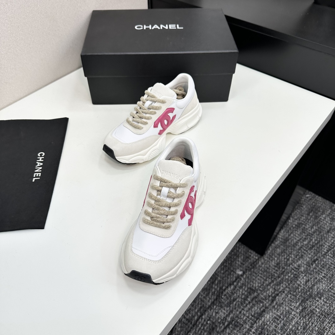 Side view of white and cream Chanel sneakers with a pink CC logo and chunky white soles on a black box. - Hình 6