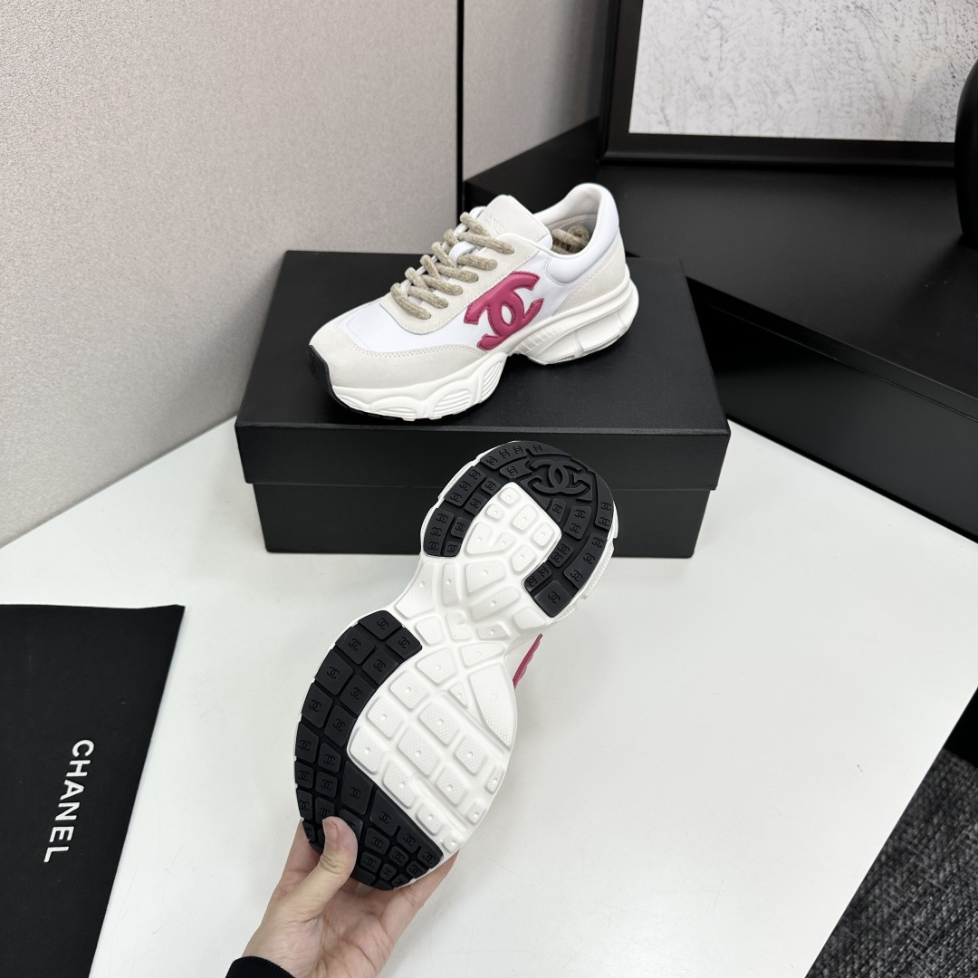 Side view of white and cream Chanel sneakers with a pink CC logo and chunky white soles on a black box. - Hình 5