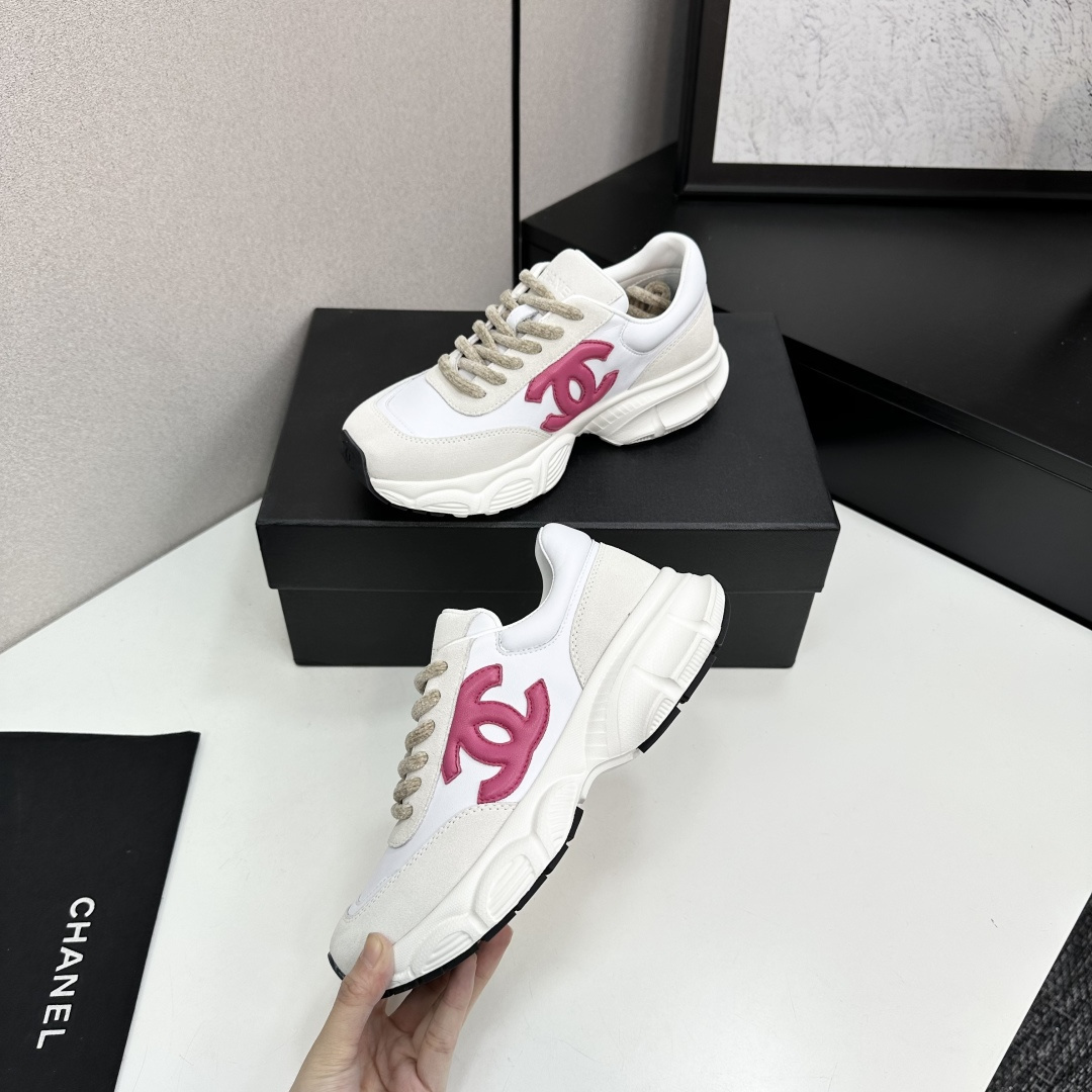 Side view of white and cream Chanel sneakers with a pink CC logo and chunky white soles on a black box. - Hình 4