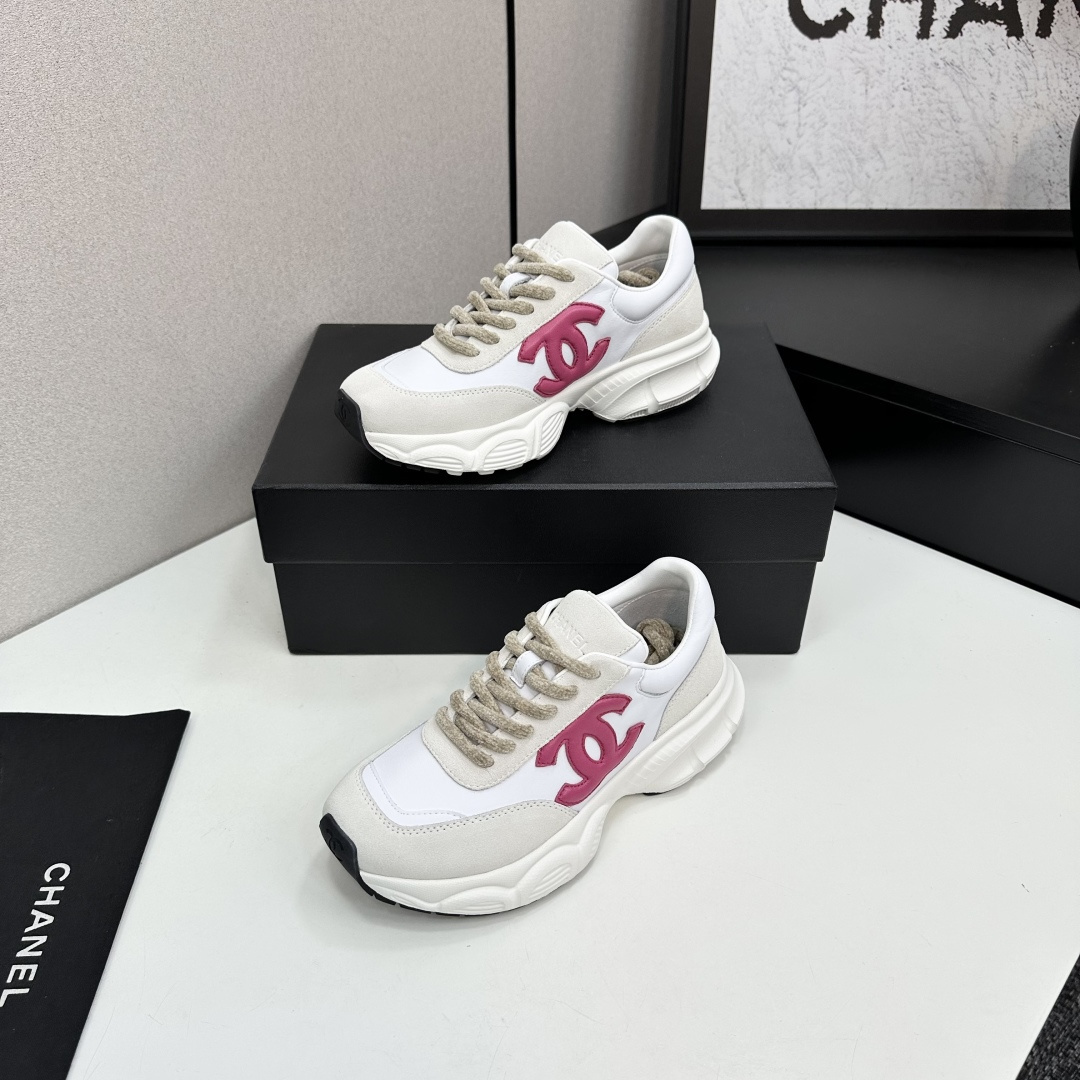 Side view of white and cream Chanel sneakers with a pink CC logo and chunky white soles on a black box. - Hình 3