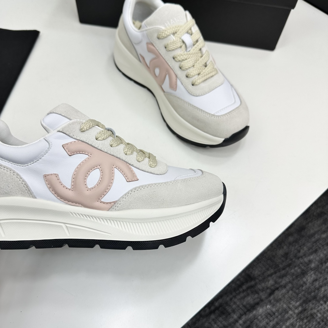 Side view of luxury white and beige sneakers with a pink interlocking CC logo on a black display box - Hình 10