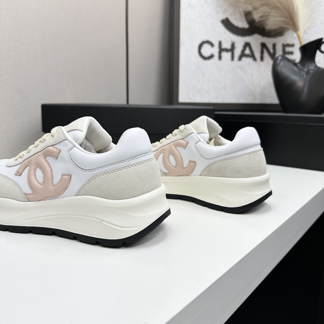 Side view of luxury white and beige sneakers with a pink interlocking CC logo on a black display box - Hình 8