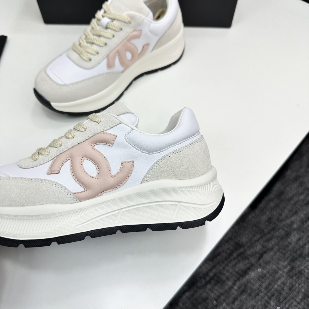 Side view of luxury white and beige sneakers with a pink interlocking CC logo on a black display box - Hình 7