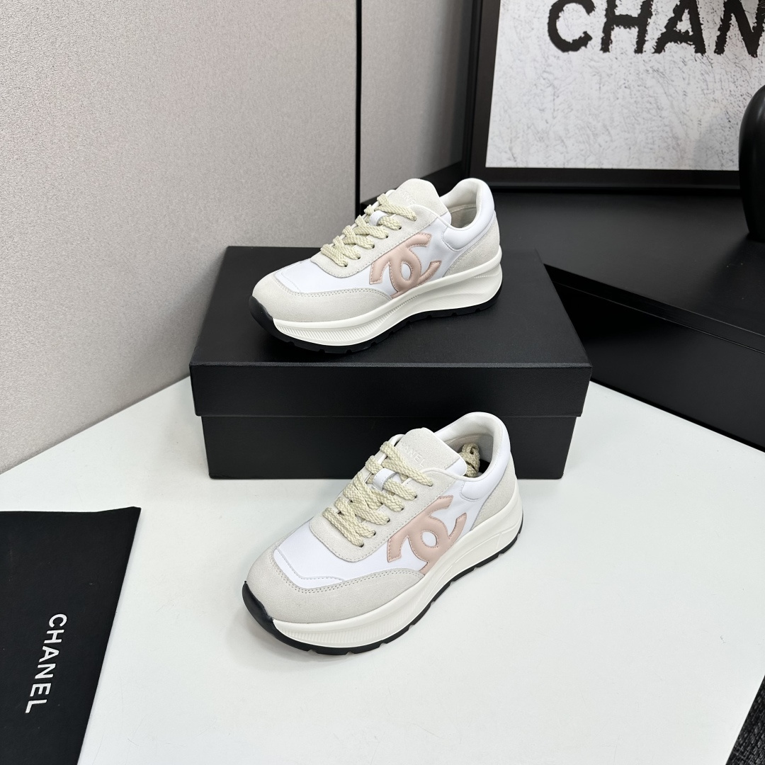 Side view of luxury white and beige sneakers with a pink interlocking CC logo on a black display box - Hình 3