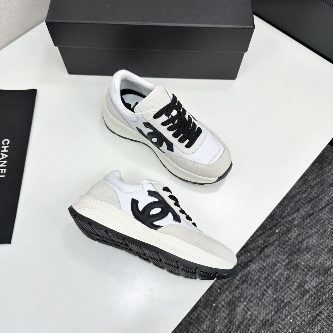 Side view of Chanel white and black leather suede sneakers with chunky soles on a black luxury box - Hình 10