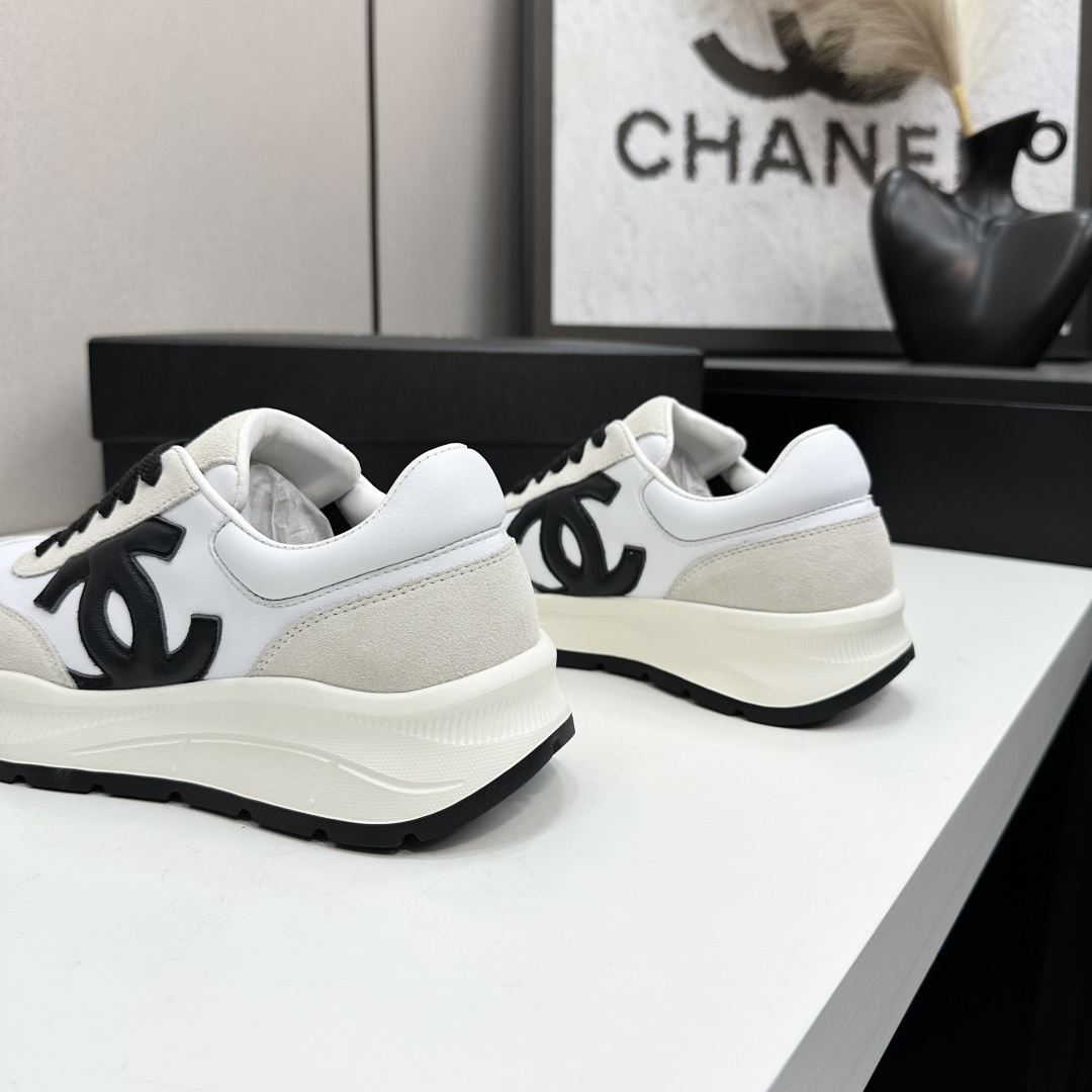 Side view of Chanel white and black leather suede sneakers with chunky soles on a black luxury box - Hình 9
