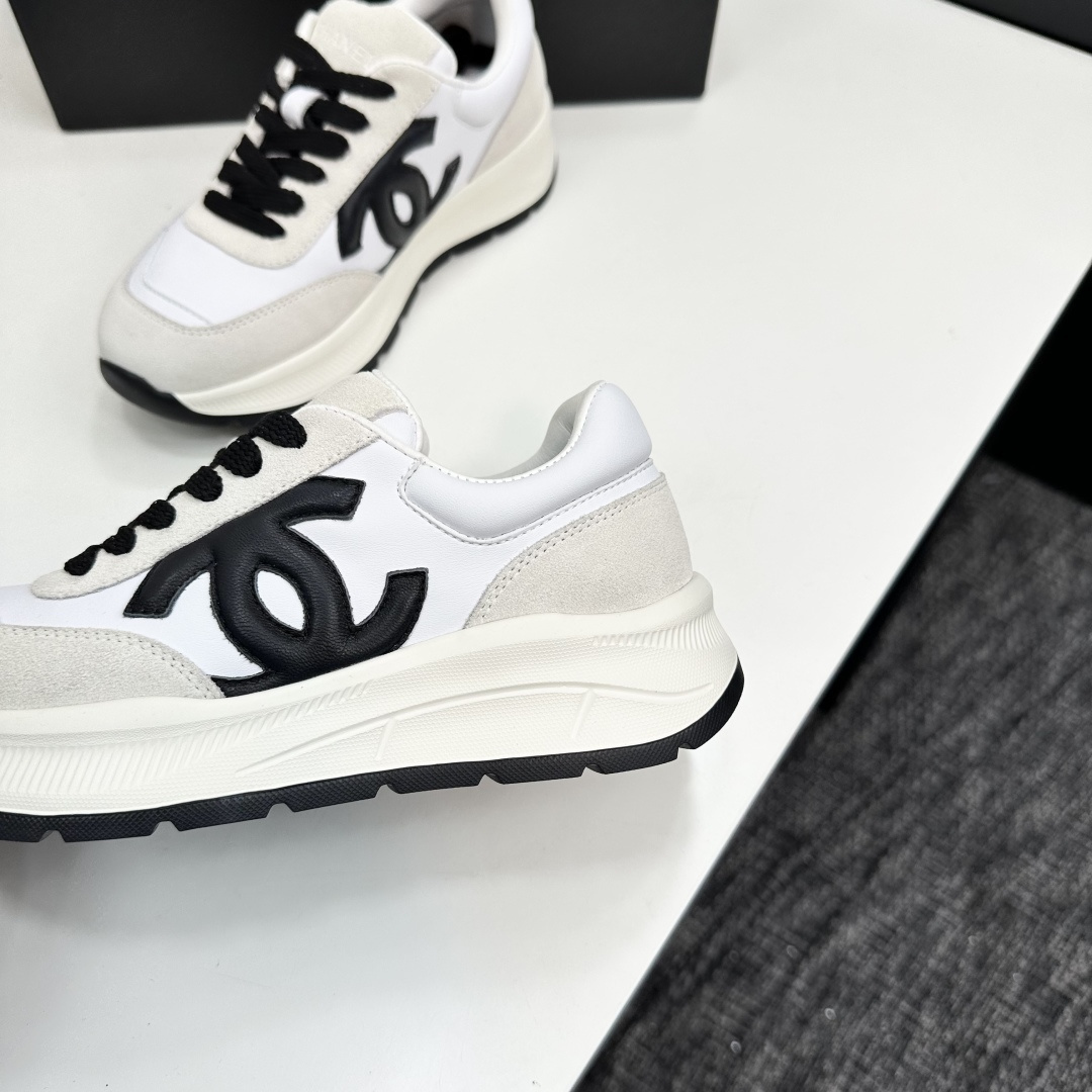 Side view of Chanel white and black leather suede sneakers with chunky soles on a black luxury box - Hình 8