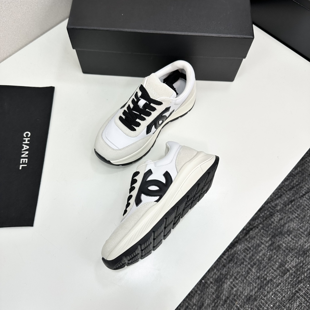 Side view of Chanel white and black leather suede sneakers with chunky soles on a black luxury box - Hình 7