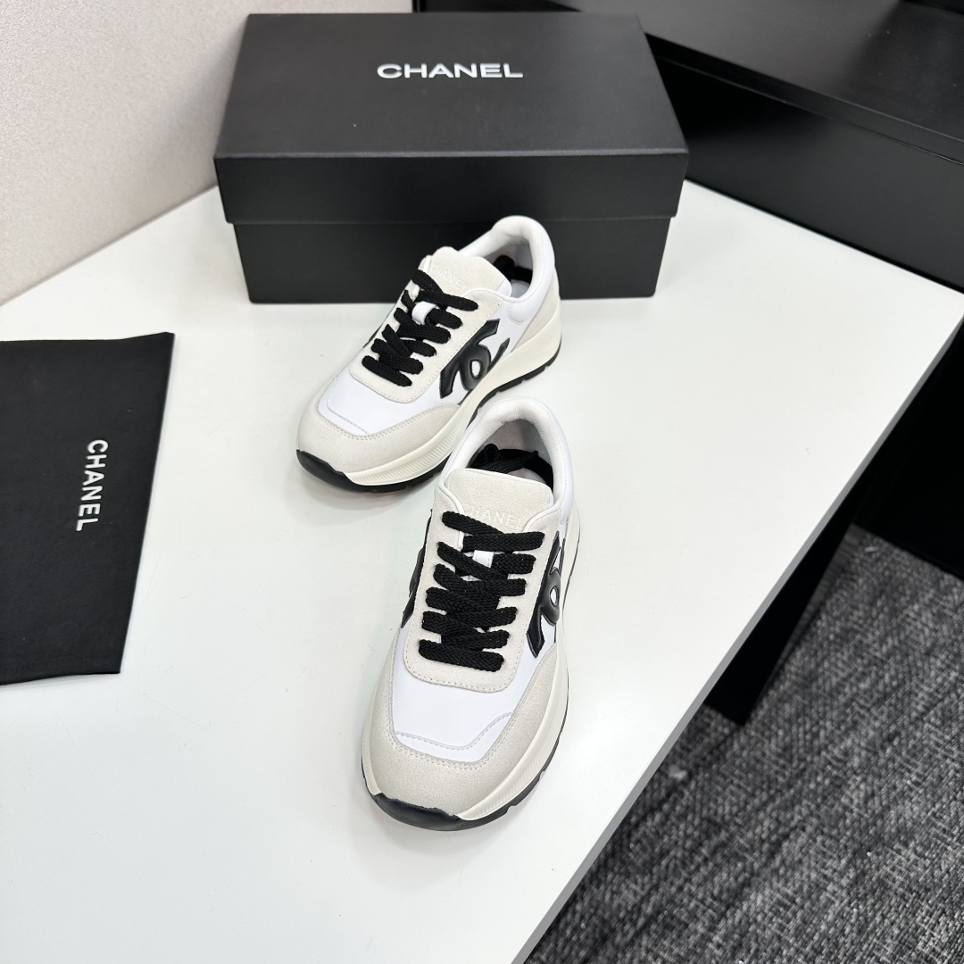 Side view of Chanel white and black leather suede sneakers with chunky soles on a black luxury box - Hình 6