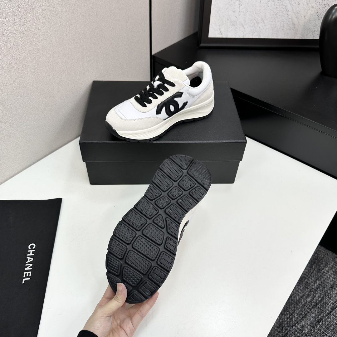 Side view of Chanel white and black leather suede sneakers with chunky soles on a black luxury box - Hình 5