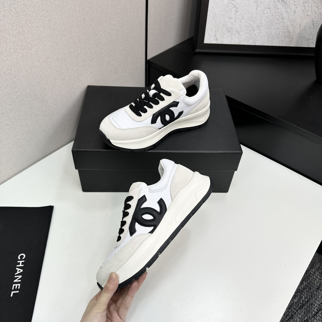 Side view of Chanel white and black leather suede sneakers with chunky soles on a black luxury box - Hình 4