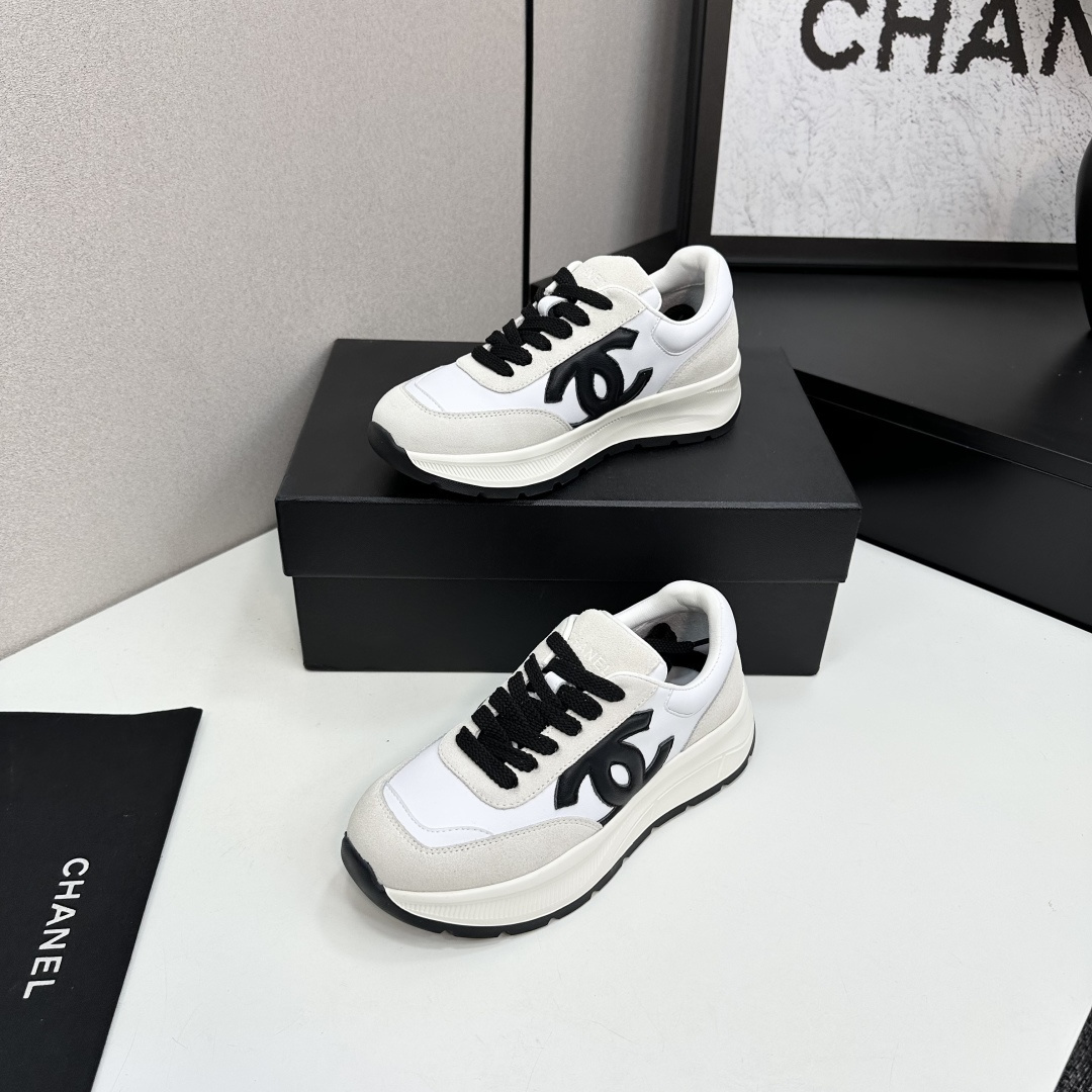 Side view of Chanel white and black leather suede sneakers with chunky soles on a black luxury box - Hình 3