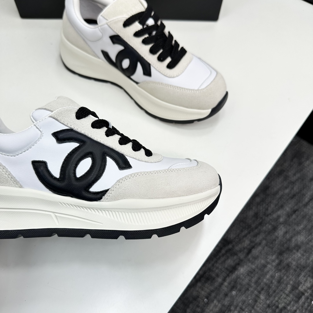 Side view of Chanel white and black leather suede sneakers with chunky soles on a black luxury box - Hình 2