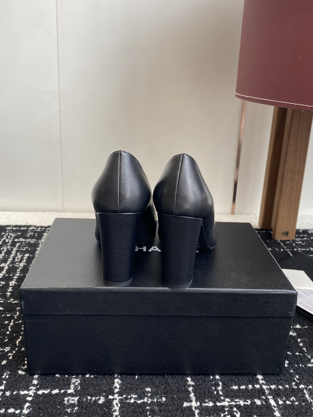 Chanel black leather square toe pumps with gold CC logo and white trim detail on a luxury shoe box - Hình 8