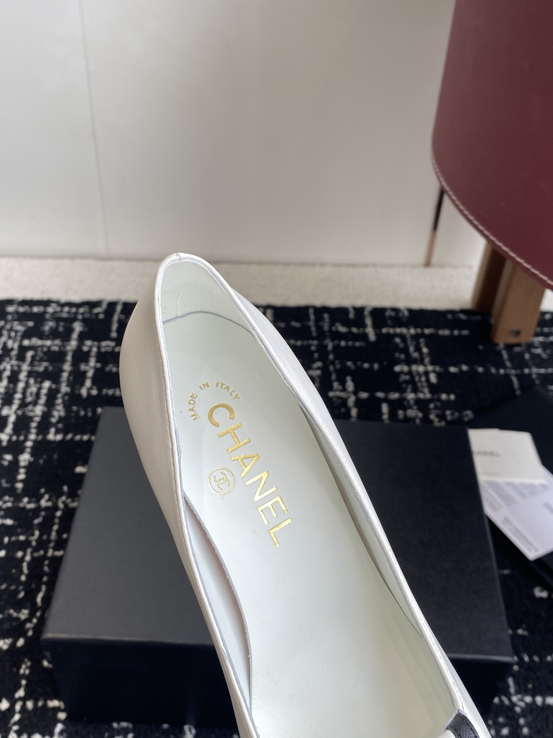 Chanel white leather pumps with black trim, gold CC logo, and block heels on a black box. - Hình 7