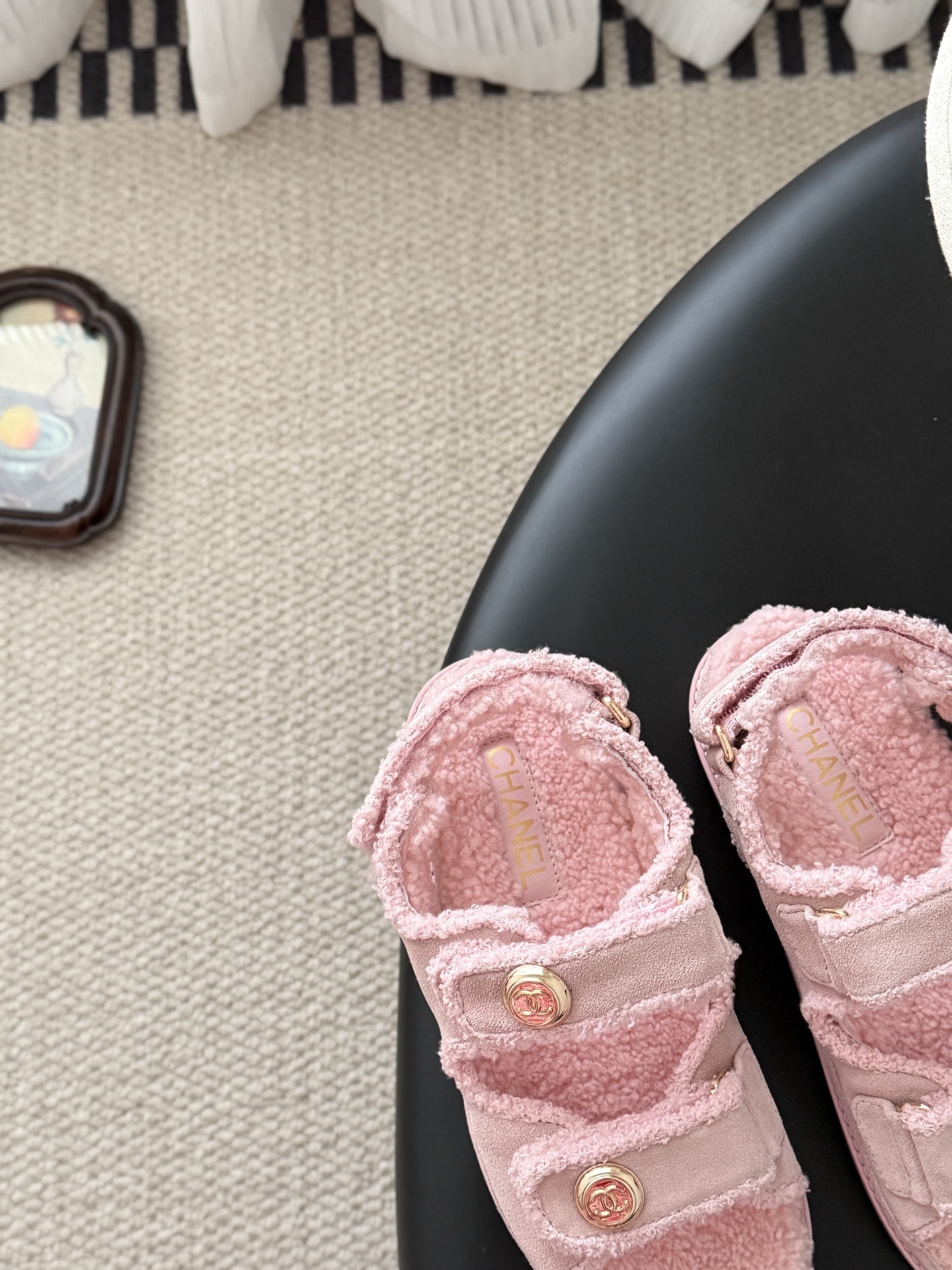 Pair of pink Chanel shearling sandals with gold CC logo buttons sitting next to a black Chanel box. - Hình 7
