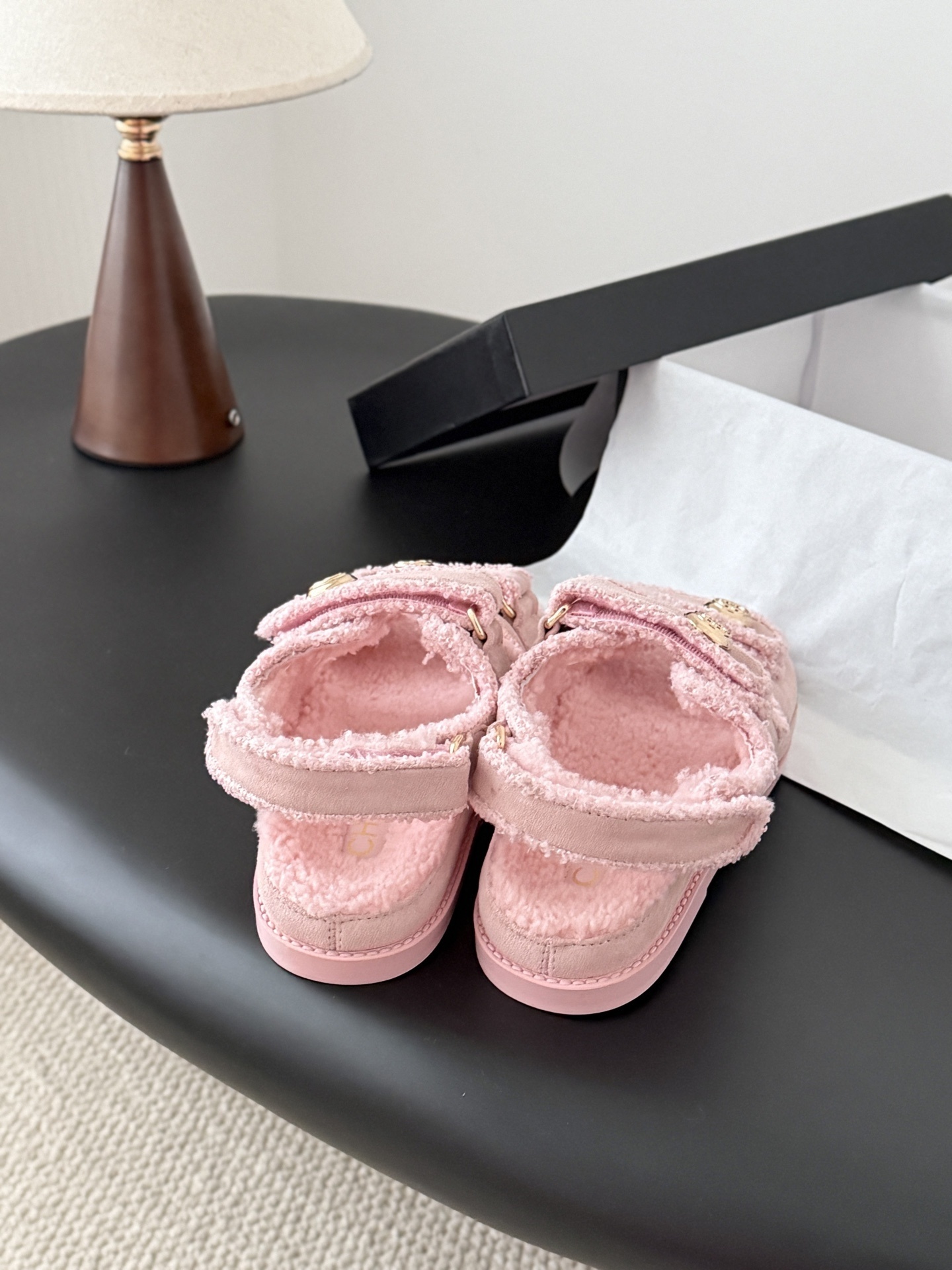 Pair of pink Chanel shearling sandals with gold CC logo buttons sitting next to a black Chanel box. - Hình 3
