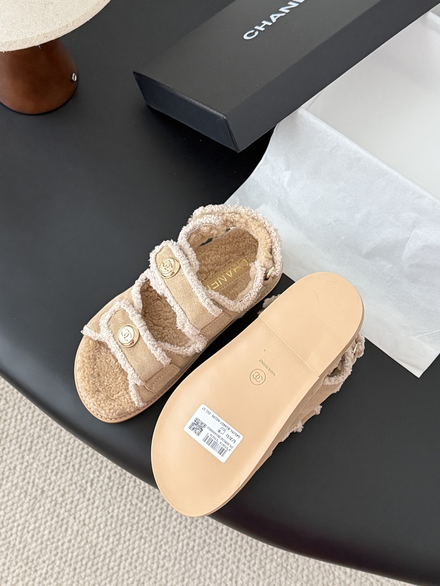 Luxury Chanel beige shearling dad sandals with gold CC logo buttons and fluffy lining placed next to a Chanel box. - Hình 7