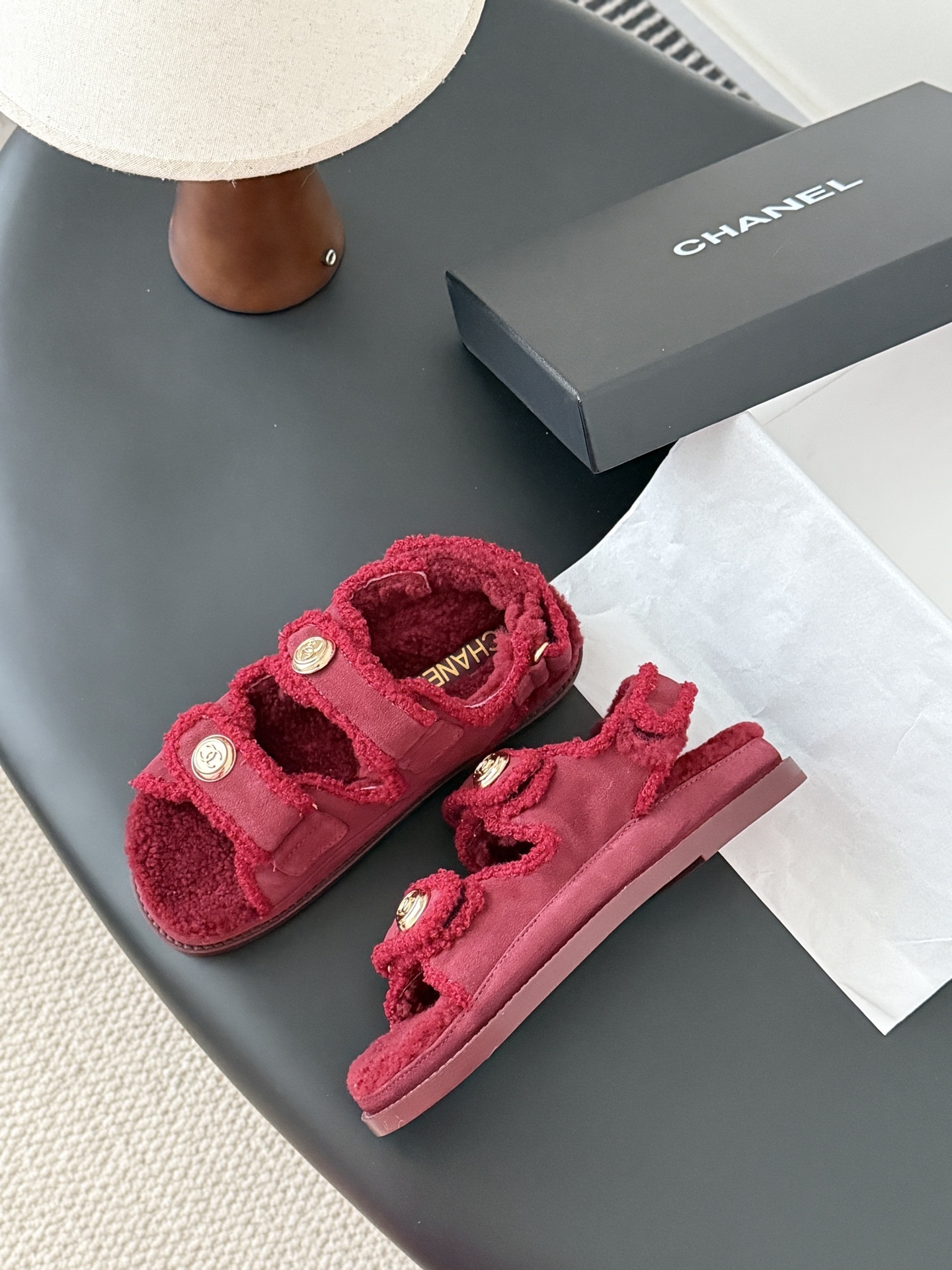 Top view of red Chanel shearling sandals with gold CC logo buttons and black designer box - Hình 4