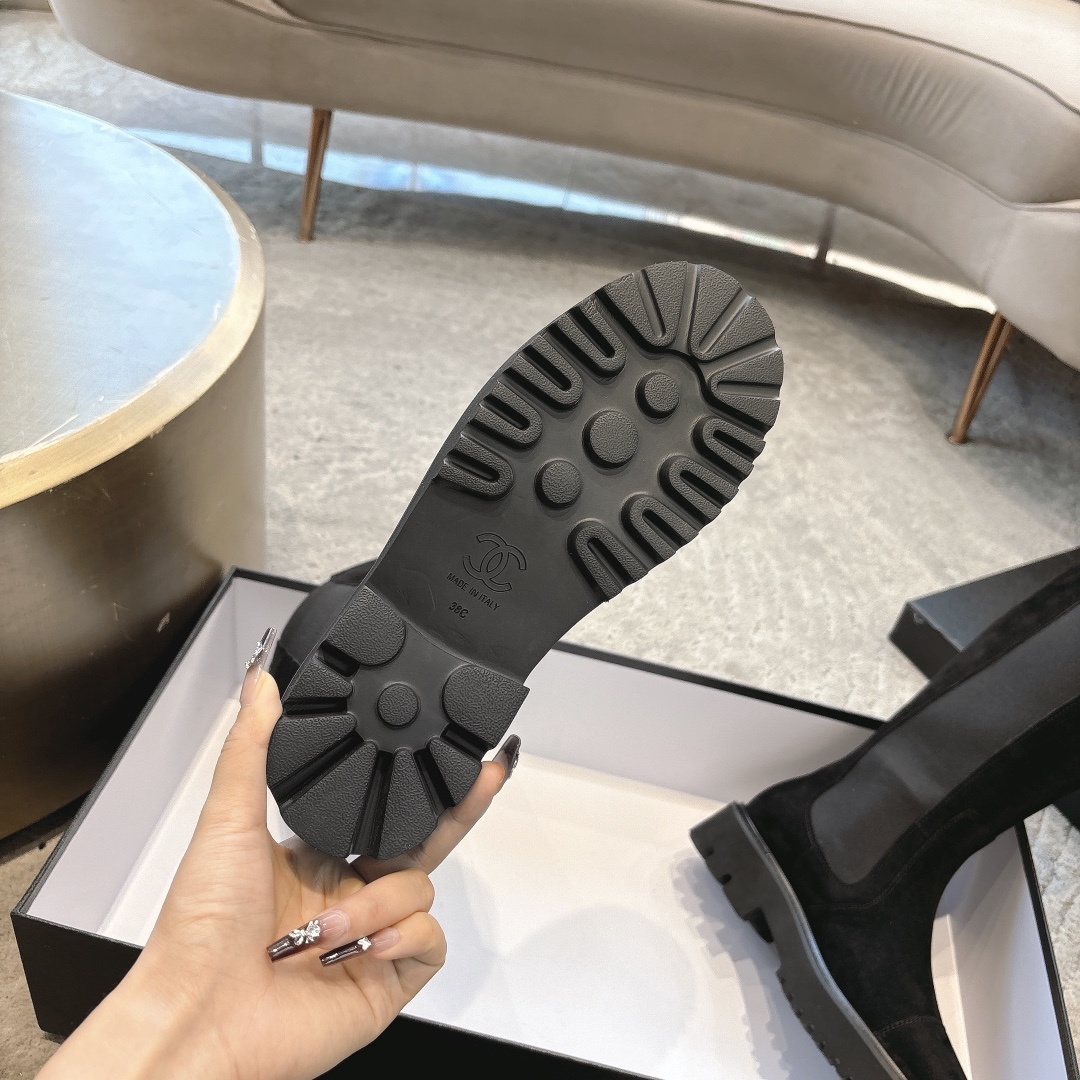 Pair of black suede knee-high boots with chunky lug soles and elastic side panels on a display box - Hình 9